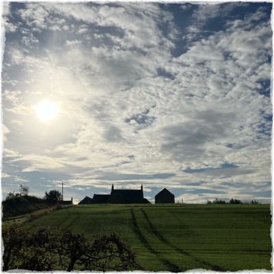 silhouette of a house against a busy sunlit sky